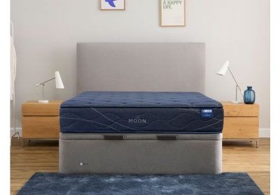 Cama com colchão azul escuro MOON e base cinza em quarto com mesas de cabeceira de madeira.