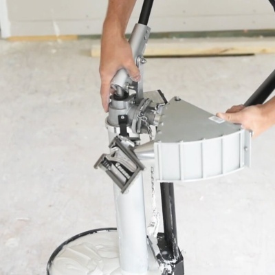 Máquina manual de pintura de parede cinza e preto com tinta branca em chão de construção