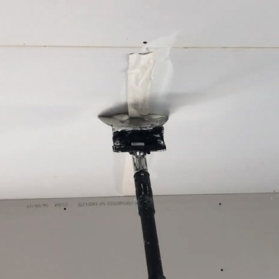 Ferramenta preta a raspar material branco numa superfície branca