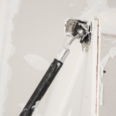 Raspador com cabo preto e suporte metálico numa superfície branca