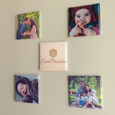 Cinco ímans quadrados com fotografias e etiqueta ComPaixão. numa parede bege