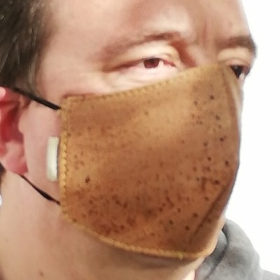 Máscara facial castanha com textura pontilhada usada por uma pessoa