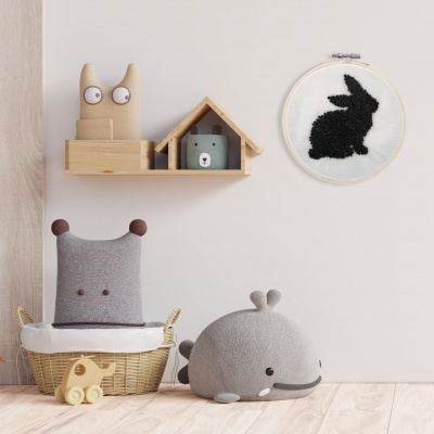 Decoração infantil com peluches animais, prateleira com gato de madeira e casa, bordado de coelho na parede.