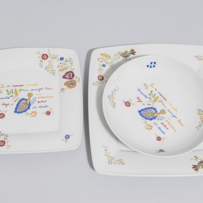 Conjunto de loiça branca com decoração floral colorida e texto manuscrito em francês.