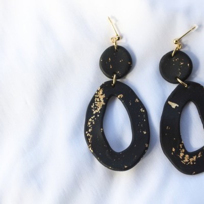 Brincos pretos com manchas douradas em fundo branco