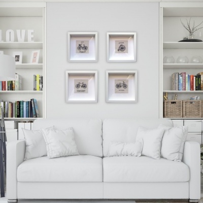 Sofá branco com almofadas, estantes com livros, cestos e quadros de bicicletas