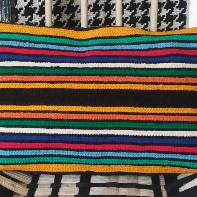 Travesseiro colorido com padrão de riscas horizontais sobre superfície pied-de-poule