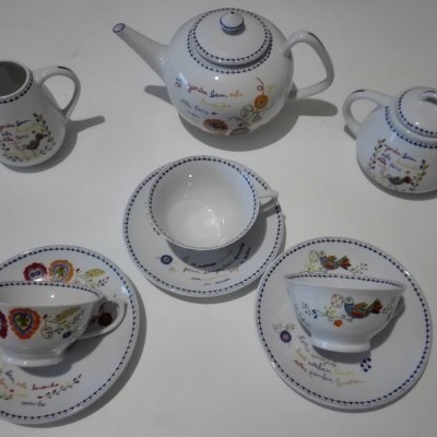 Conjunto de chá de porcelana branca decorado com flores coloridas e bordas azuis.