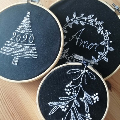 Três aros de bordado com desenhos brancos em tecido preto