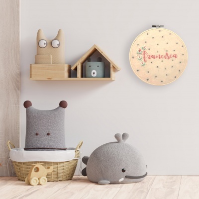 Ambiente infantil com brinquedos de pelúcia, prateleira de madeira, urso azul em casa de madeira e bastidor de bordado com nome 'Francisa'