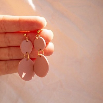 Brincos ovais cor-de-rosa claros pendurados em fundo neutro