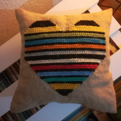 Almofada bege com coração colorido em crochet