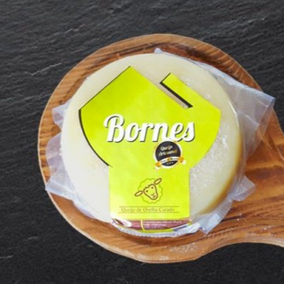 Queijo redondo embalado com etiqueta amarela e texto Bornes sobre tábua de madeira.