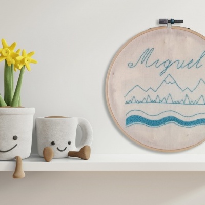 Vasos de tecido com faces sorridentes e bastidor bordado com nome Miguel