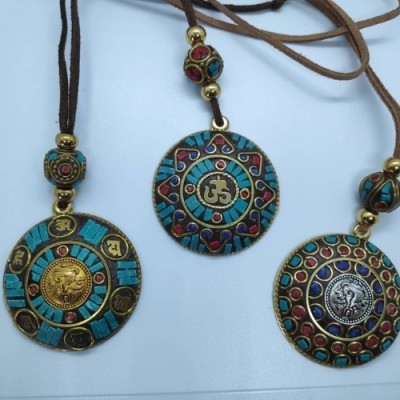 Três colares com pendentes redondos coloridos em metal e cordões castanhos.