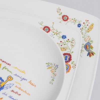 Prato de louça branca decorado com flores coloridas e texto em português