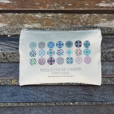 Bolsa bege com padrão de azulejos coloridos e texto, sobre banco de madeira