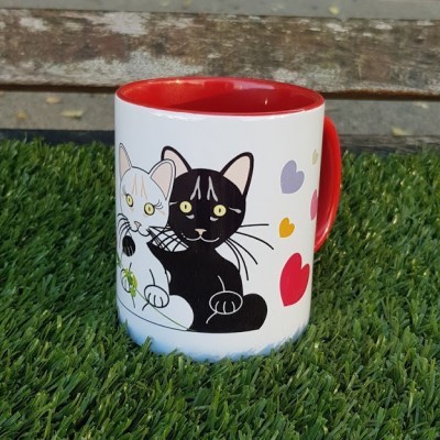 Caneca branca com interior e pega vermelhos e ilustração de gatos e corações.
