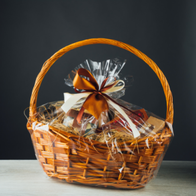 Cesto de verga com pacote em celofane e fita castanha e branca