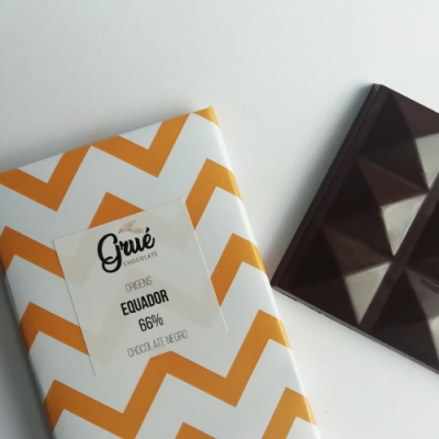 Barra de chocolate negro 66% cacau em embalagem branca com padrão amarelo e pedaço do chocolate ao lado