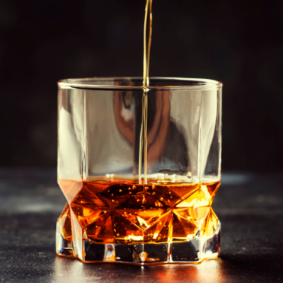 Copo de vidro com líquido âmbar a ser vertido