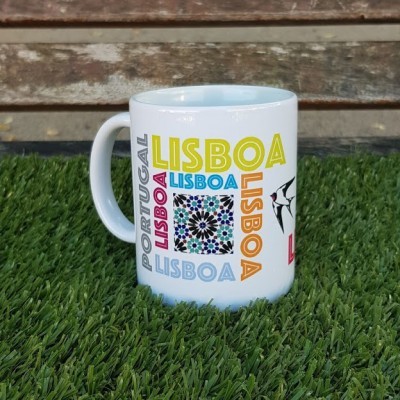 Caneca branca com várias palavras Lisboa em diferentes cores e padrões num fundo de relva artificial