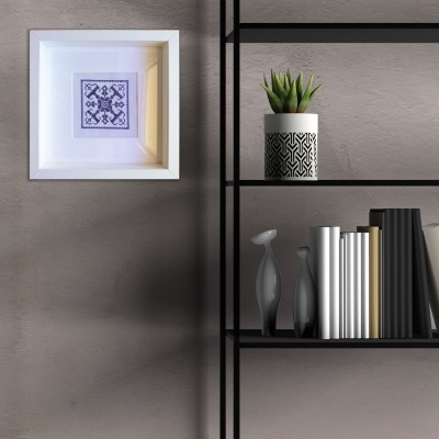 Prateleira preta com vasos decorativos e livros ao lado de um quadro branco com padrão azul abstrato numa parede cinza