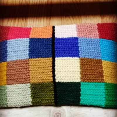 Almofada quadrada com padrão de quadrados coloridos em tecido de malha