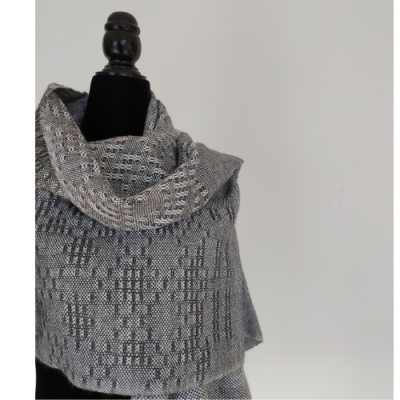 Cachecol cinzento e branco com padrão tecido num manequim preto