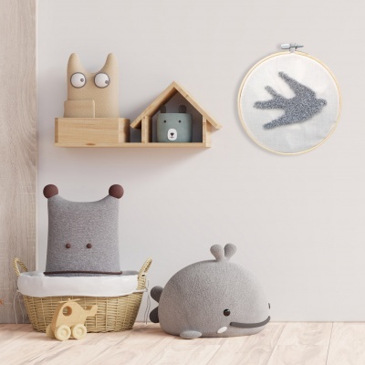 Área de criança com almofadas de pelúcia, brinquedos e decoração de parede em tons neutros.