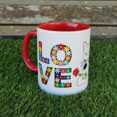 Caneca branca com interior e pega vermelha, com a palavra LOVE colorida e um gato desenhado.
