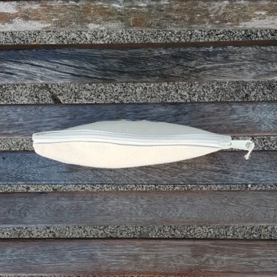 Estojo branco com fecho de correr sobre madeira e pedra