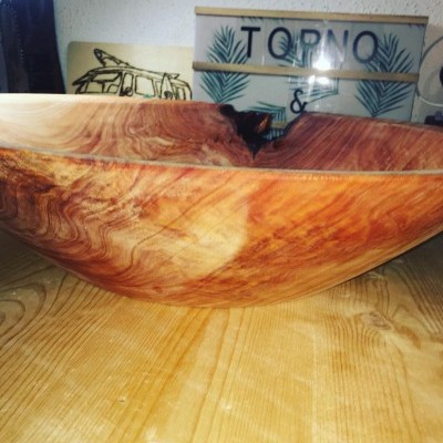 Taça de madeira grande com padrão natural sobre mesa de madeira e caixa decorativa ao fundo