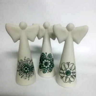 Três anjos decorativos de cerâmica branca com padrões florais verdes e pretos.