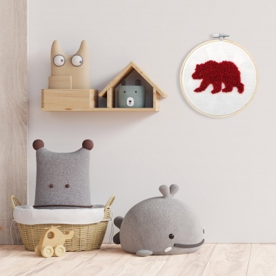 Decoração infantil com almofadas de baleia e monstro, prateleiras e bordado de urso vermelho
