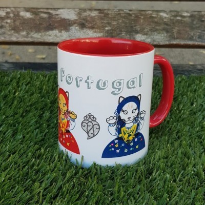 Caneca branca com desenhos coloridos e palavra Portugal, sobre relva artificial