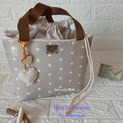 Saco cinza com corações brancos e alças castanhas, com decoração de corações e etiqueta