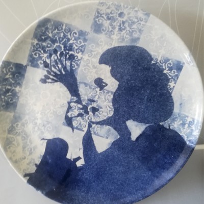 Prato com padrão azul e branco e silhuetas de personagem feminina e criança