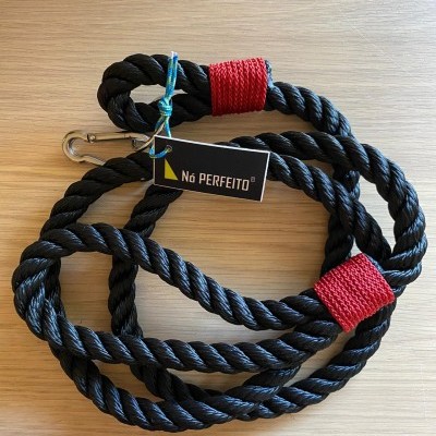 Corda preta grossa com pontas vermelhas e etiqueta Nó PERFEITO sobre madeira.