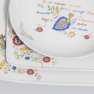 Conjunto de pratos brancos com estampas florais coloridas e texto em português