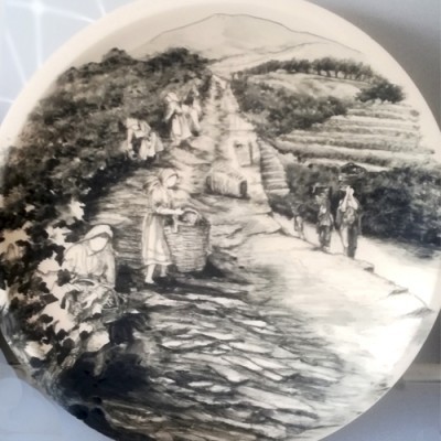 Prato decorativo preto e branco com desenho de pessoas a trabalhar na vinha