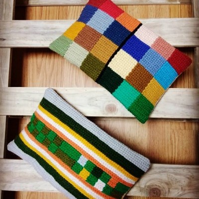 Duas almofadas retangulares em crochet colorido sobre pallet de madeira clara