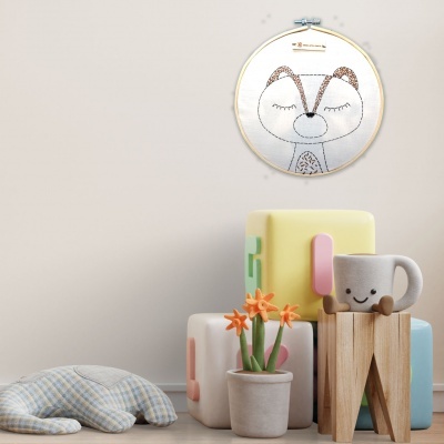 Almofada azul, blocos de construção, vaso com flores, caneca sorridente e bordado de raposa em moldura redonda