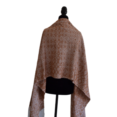 Xale tecido com padrão geométrico castanho e branco num manequim preto
