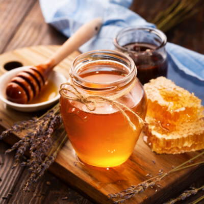 Frasco de mel com favo de mel e utensílio para mel em superfície de madeira