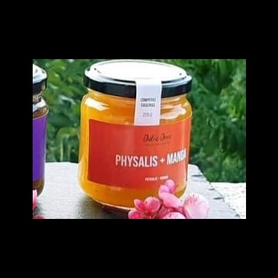 Frasco de creme physalis e manga com rótulo vermelho em superfície com flores