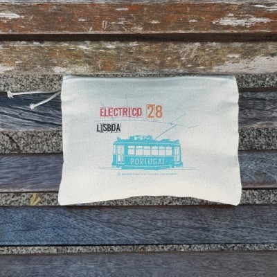 Bolsa de tecido estampada com elétrico 28 Lisboa sobre banco de madeira