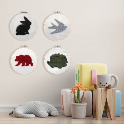 Quadros bordados de coelho, pássaro, urso e ouriço em parede, almofada, vaso com flores, cubos coloridos e caneca sorridente no chão