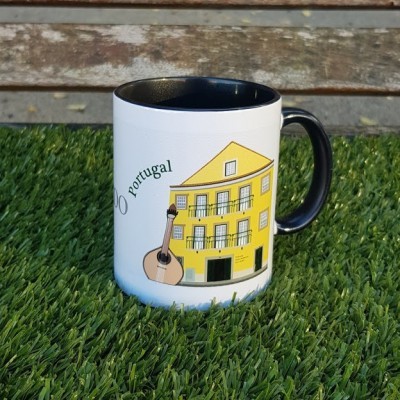 Caneca branca com ilustração de edifício amarelo e guitarra, texto 'portugal', sobre relva sintética