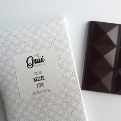 Barra de chocolate negro e embalagem branca com texto e padrão geométrico